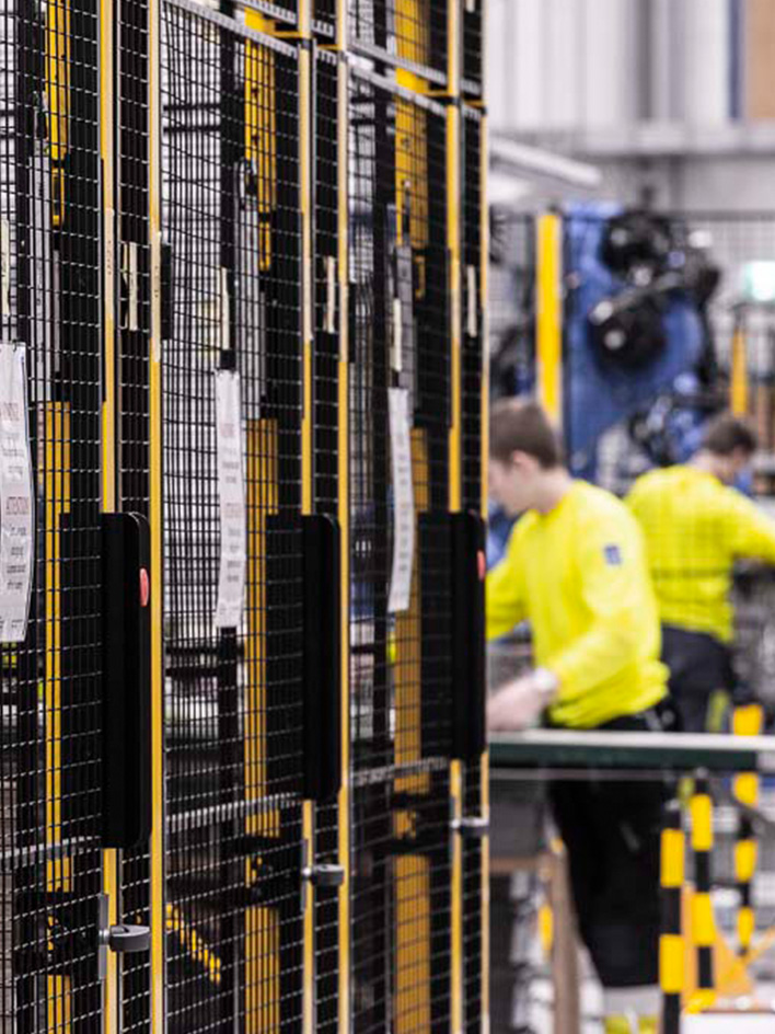 Warehouse with safety barriers and workers near machinery, highlighting risks where people and automation interact