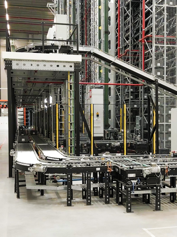 Automated roller and belt conveyor system in a warehouse, used for transporting totes and bins