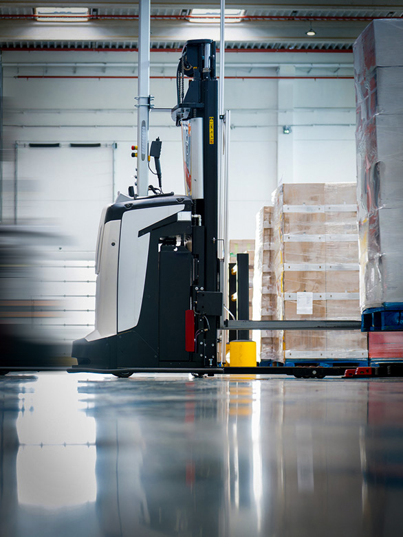 An AVG transports a pallet in a warehouse for automated material handling