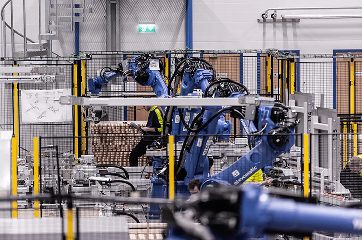 Industrial robotic arms palletizing goods inside secured automation cell